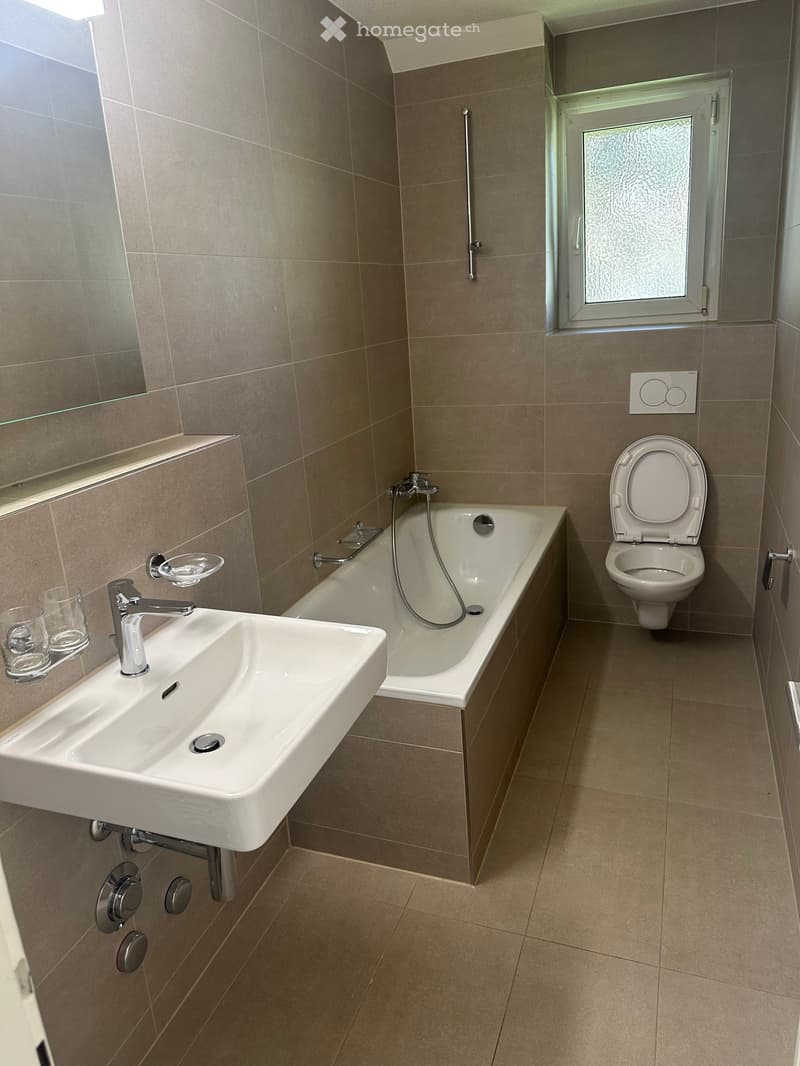 Bathroom with bathtub, toilet, sink, mirror, and tiled flooring