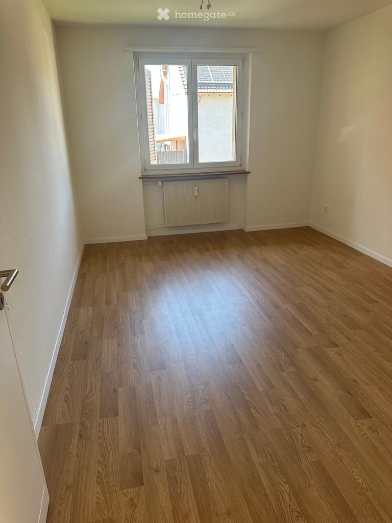 empty room, wooden floor, white walls, window with white shutters, radiator