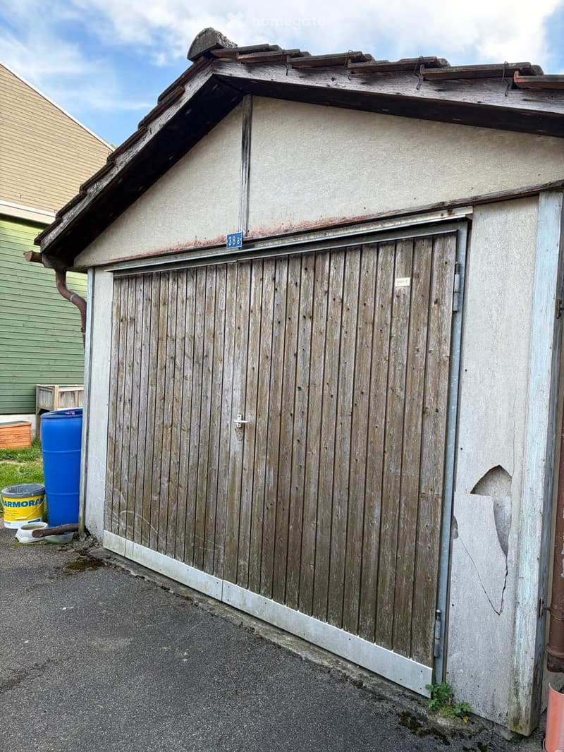 Wooden garage door, number 388, concrete wall, metal gutter, blue barrel, yellow bucket