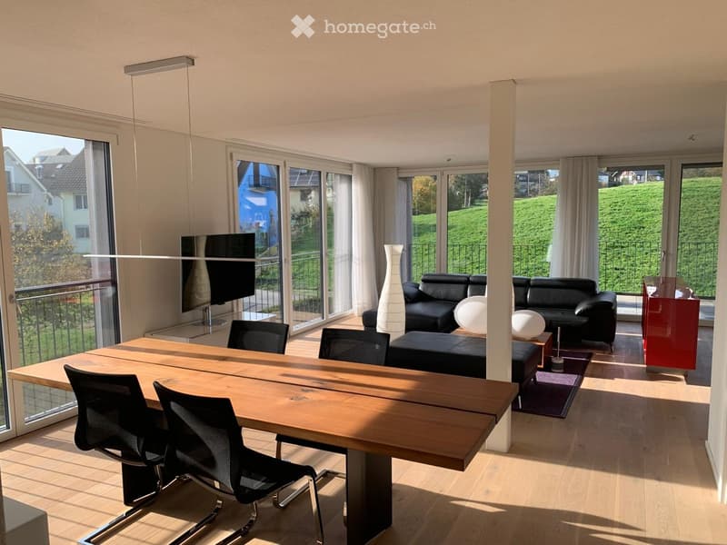 large living room with dining table, black leather sofa, TV, wooden floor, large windows, balcony