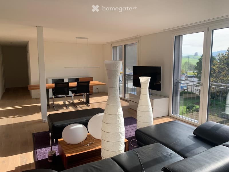 modern living room with black leather sofa, wooden coffee table, dining table with chairs, TV, large windows with balcony, wooden floor