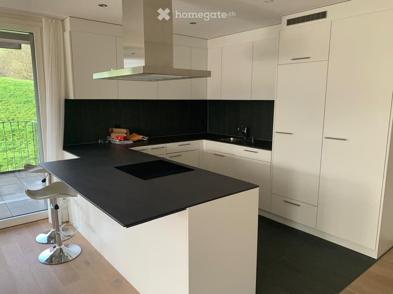 modern kitchen with black countertops, white cabinets, island with stools, glass door to balcony, black tiled floor