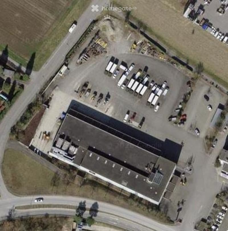 Industrial building with a large parking lot, multiple trucks and cars parked