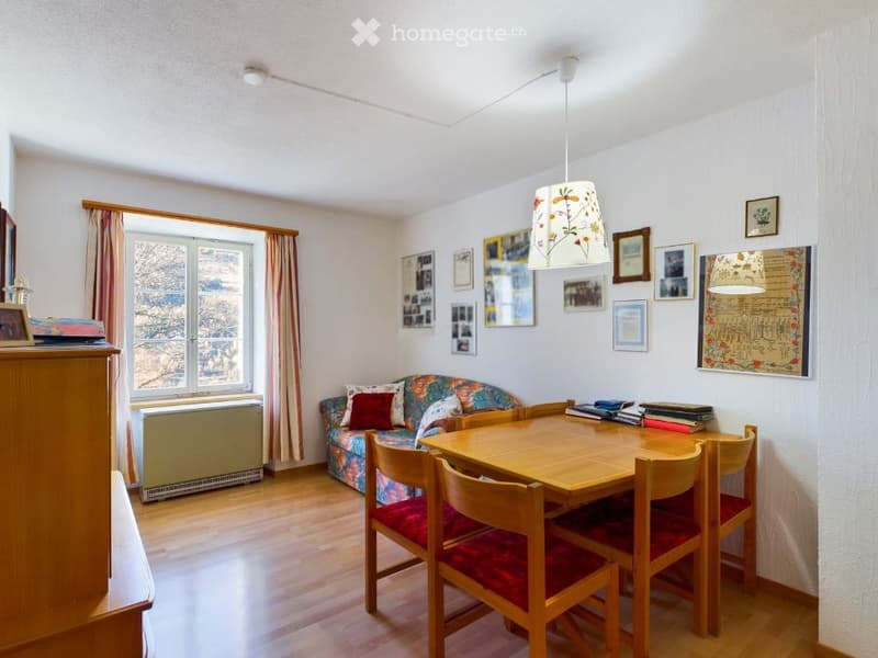 dining room with wooden table, chairs, couch, window with curtains, picture frames on the wall, wooden cabinet, radiator