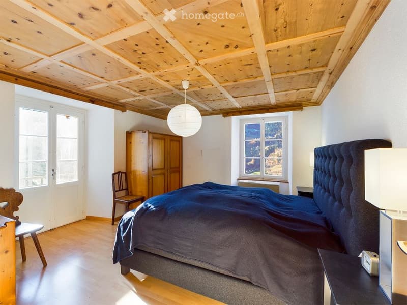 Bedroom with wooden ceiling, wooden floor, bed, wooden cabinet, chair, windows, lamps
