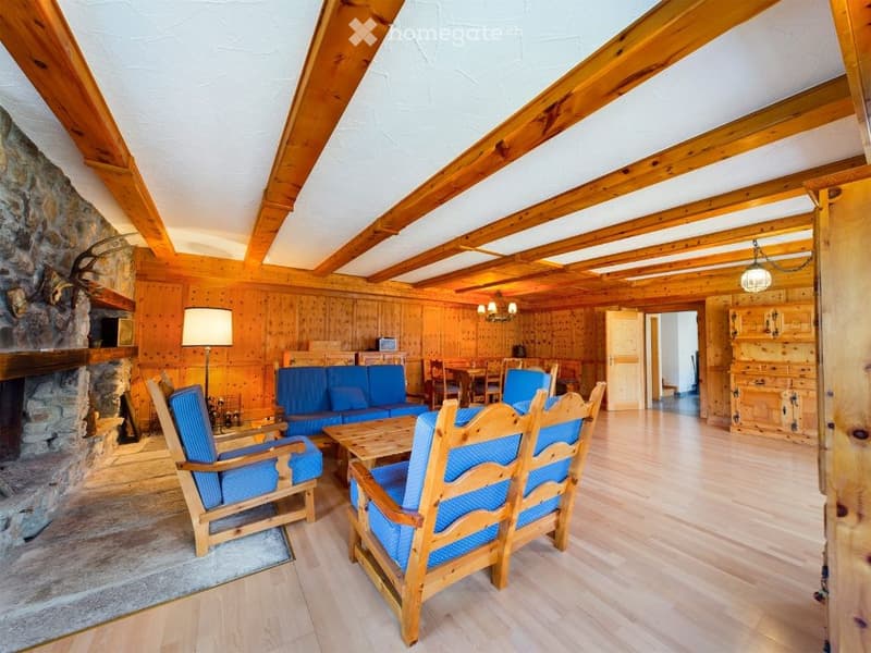 wooden beams, wooden floor, blue sofa, wooden chairs, wooden table, fireplace, wooden cabinets, lamp