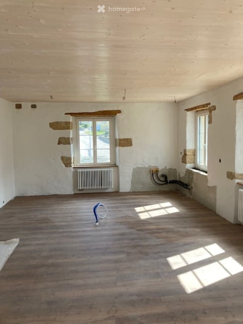 empty room, wooden floor, white walls, two windows, radiator, unfinished walls