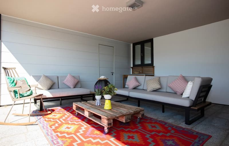 outdoor seating area with two couches, a coffee table, a rocking chair, and a rug