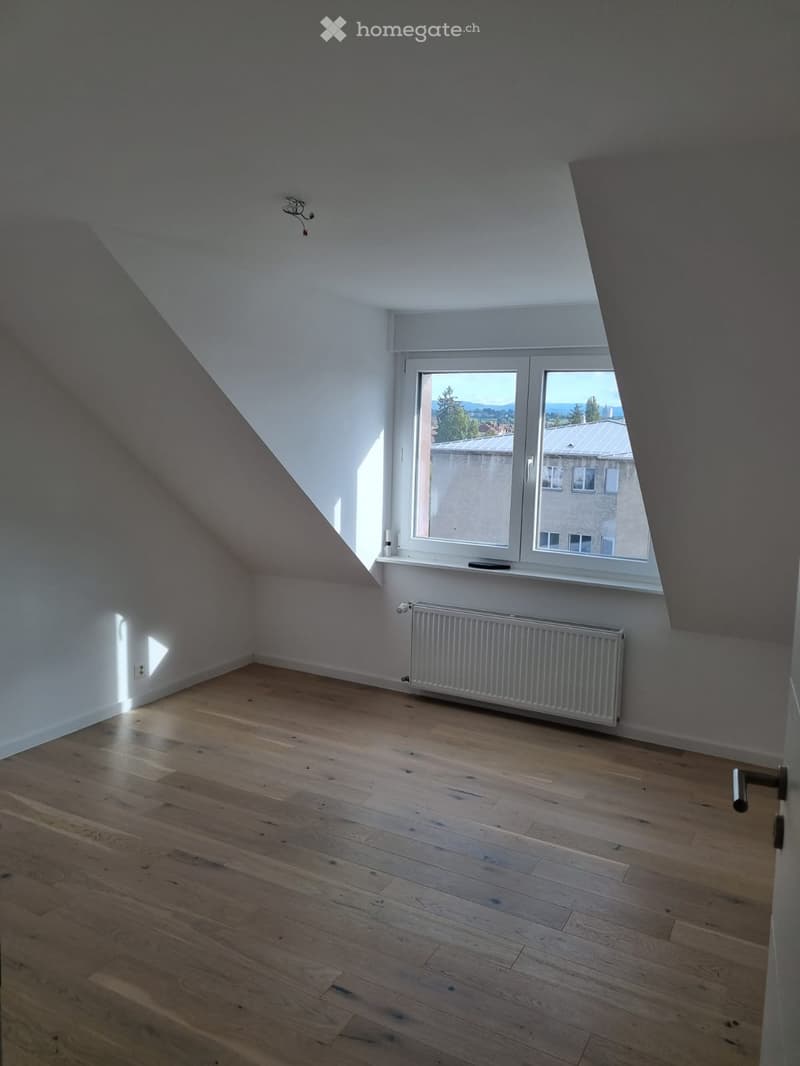 empty room, wooden floor, white walls, window, radiator, slanted ceiling
