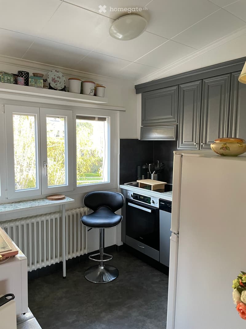 kitchen with white appliances, gray cabinets, black bar stool, white radiator, white table, large windows