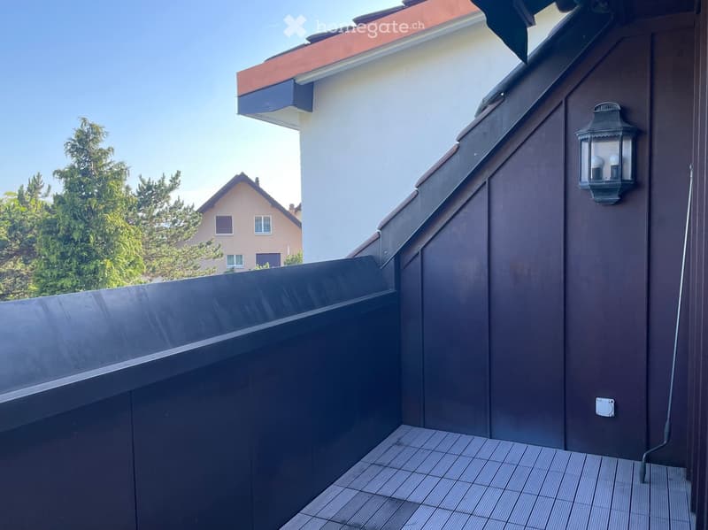 Balcony with dark wooden railing, tiled floor, and a lantern-style wall light fixture.