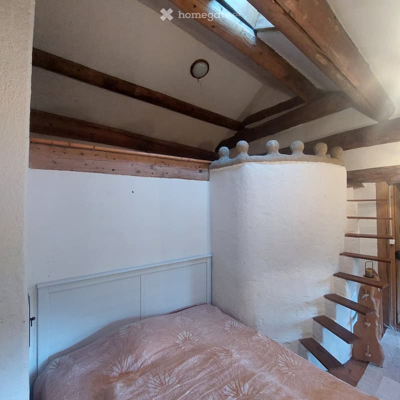 bedroom with bed, wooden ceiling, white walls, wooden stairs