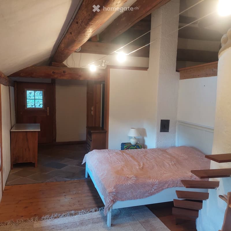 bedroom with bed, nightstand, lamp, wooden floor, wooden beams, wooden cabinet, rug, wooden door