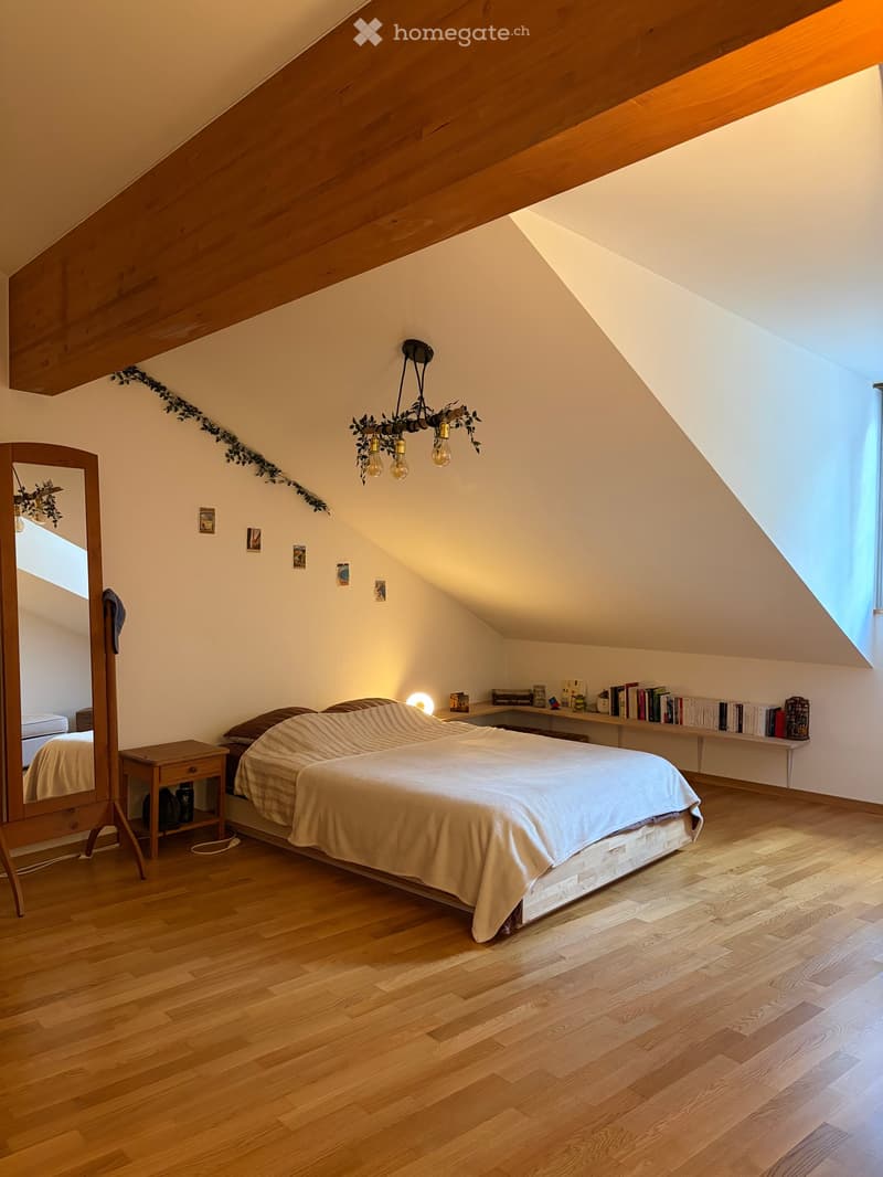 bedroom with wooden floor, bed, nightstand, mirror, chandelier, books on shelf