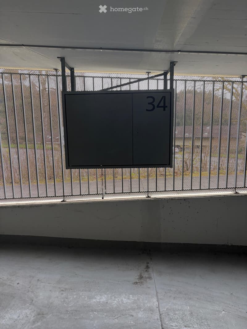 Parking area with a number 34 sign, metal fence, concrete floor