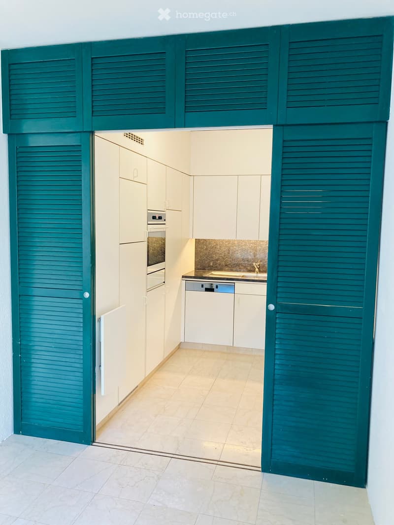 modern kitchen with white cabinets, teal sliding doors, marble countertop, dishwasher, oven, sink, faucet