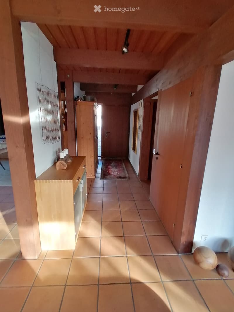 wooden beams, tiled floor, wooden cabinet, rug, wooden doors, wall art, light fixtures
