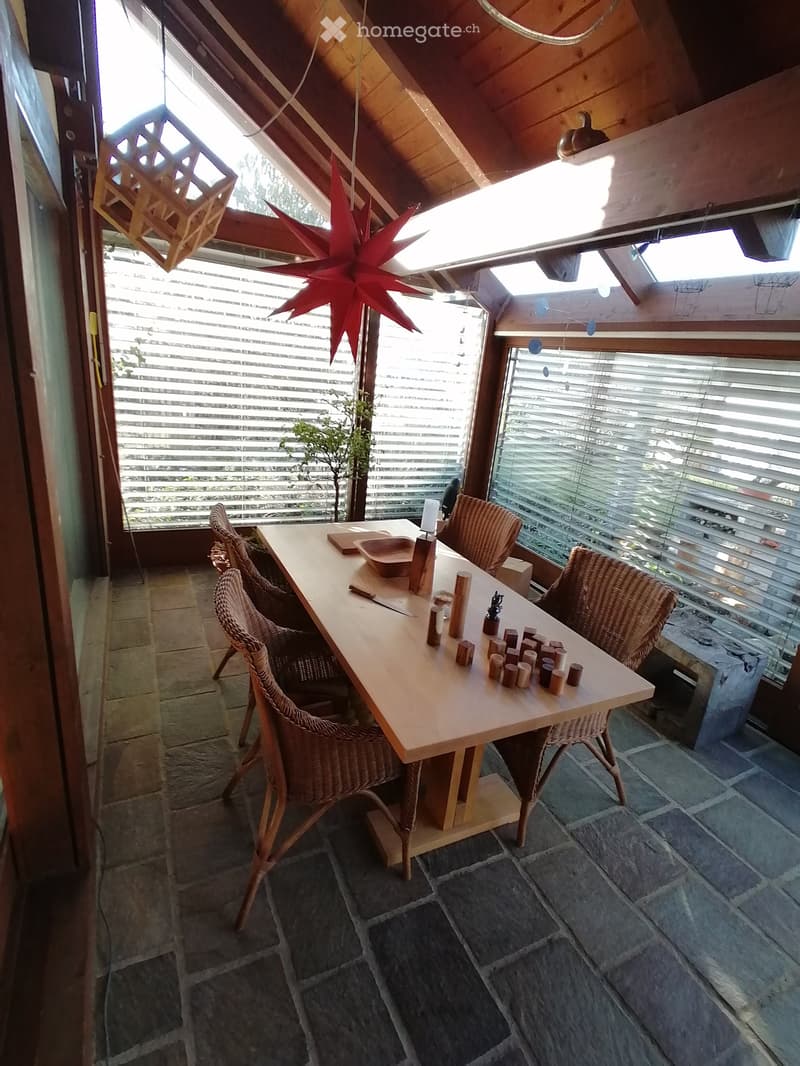 Dining area with wooden table, wicker chairs, wooden floor, large windows, wooden beams, red star decoration