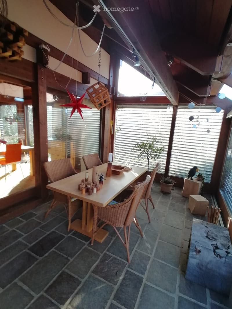 dining area with wooden table and chairs, wooden floor, glass windows, plants, wooden stools, hanging decorations