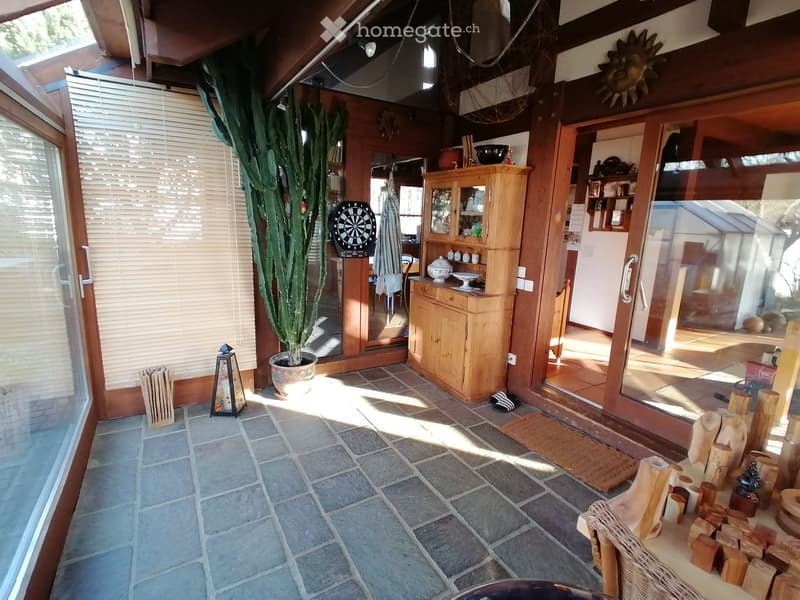 large windows, wooden floor, wooden cabinet, potted plant, dartboard, lantern, rug
