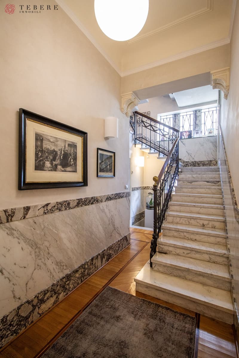 marble wall, wooden floor, marble staircase, black handrail, picture frames, lamp