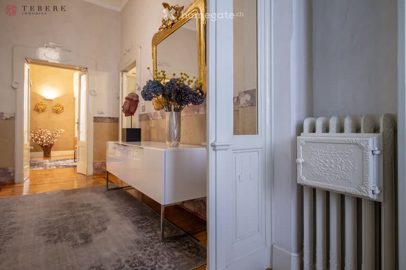 white walls, wooden floor, white console table, gold mirror, white radiator, gray carpet, flowers in vase