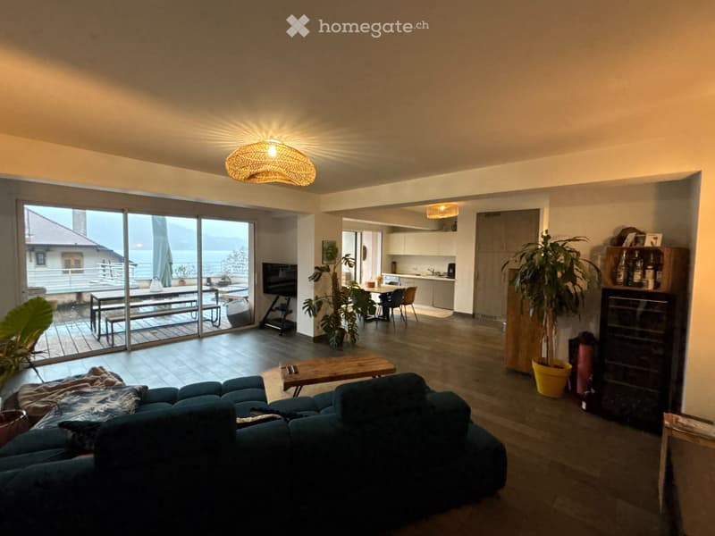large living room with wooden floor, large windows, sliding glass doors to balcony, sofa, coffee table, plants, wine cooler, TV