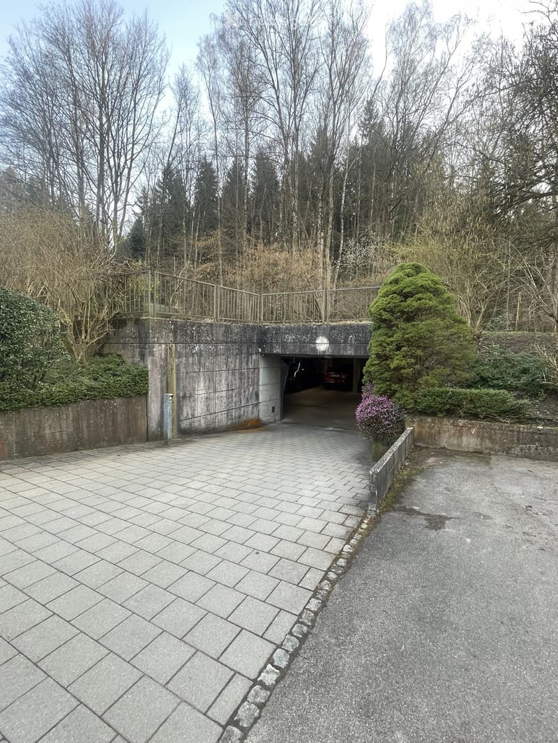 A concrete building with a tunnel entrance, leading to a parking area with a car parked inside.