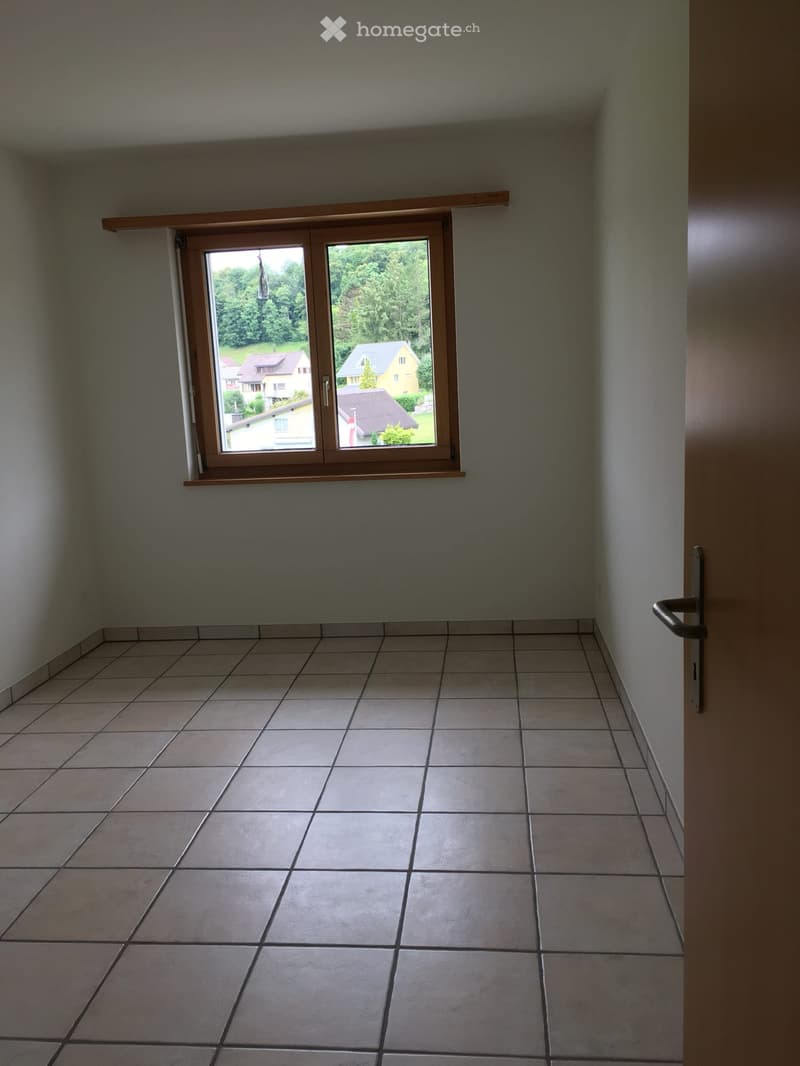 empty room, white walls, tiled floor, window with view of houses and trees