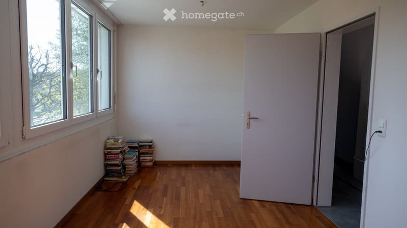 empty room, wooden floor, white walls, large windows, stack of books