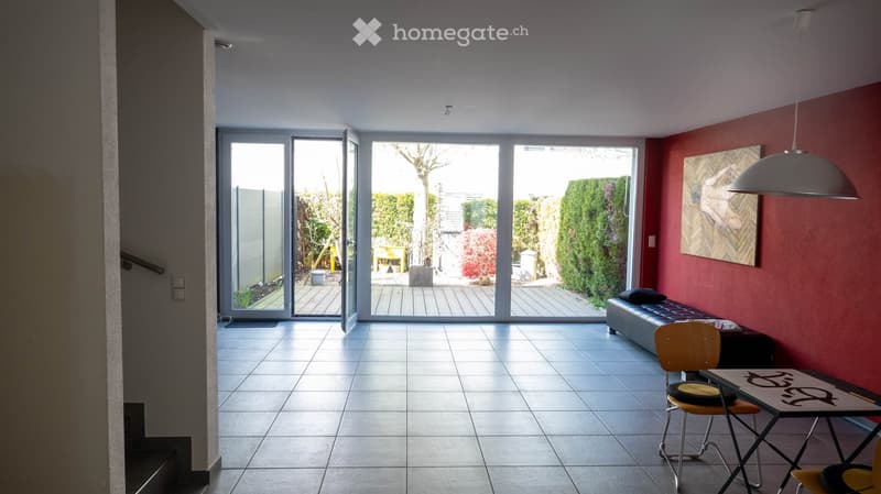 open space, large windows, tiled floor, red wall, black couch, table, chairs, lamp