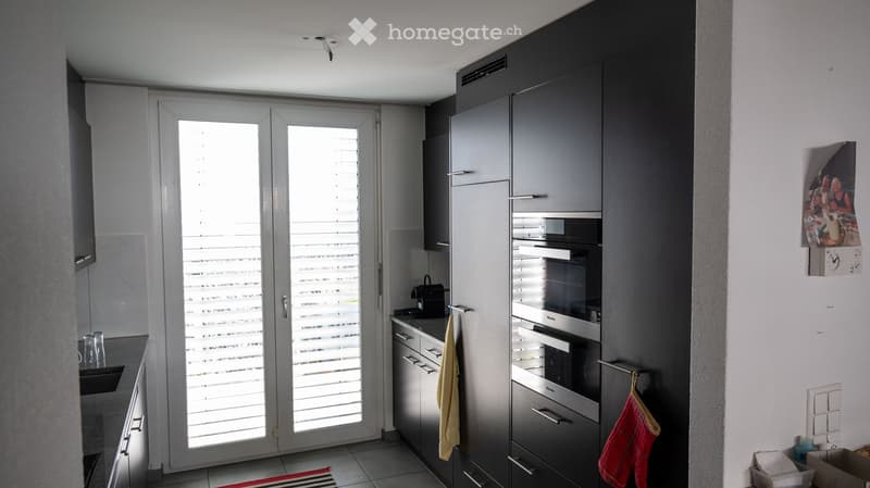 modern kitchen, black cabinets, stainless steel appliances, double oven, sink, countertop, double doors leading to balcony