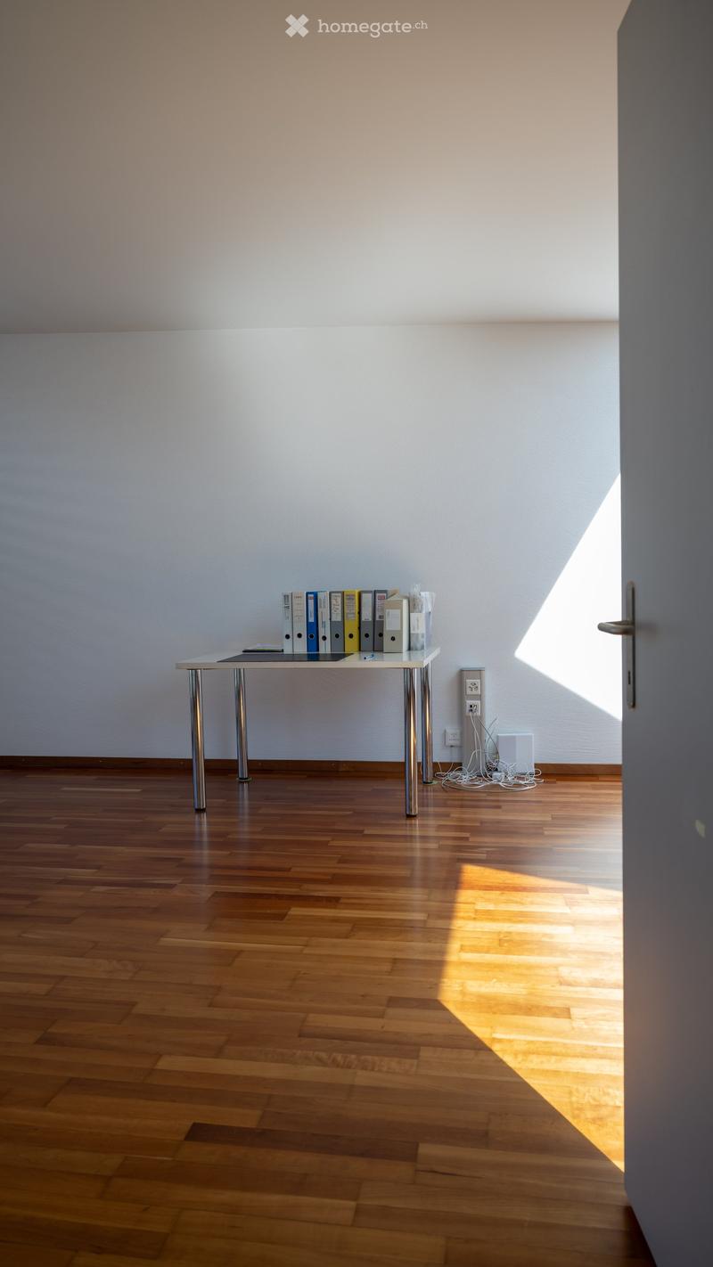 empty room, white walls, wooden floor, desk with files, power outlet