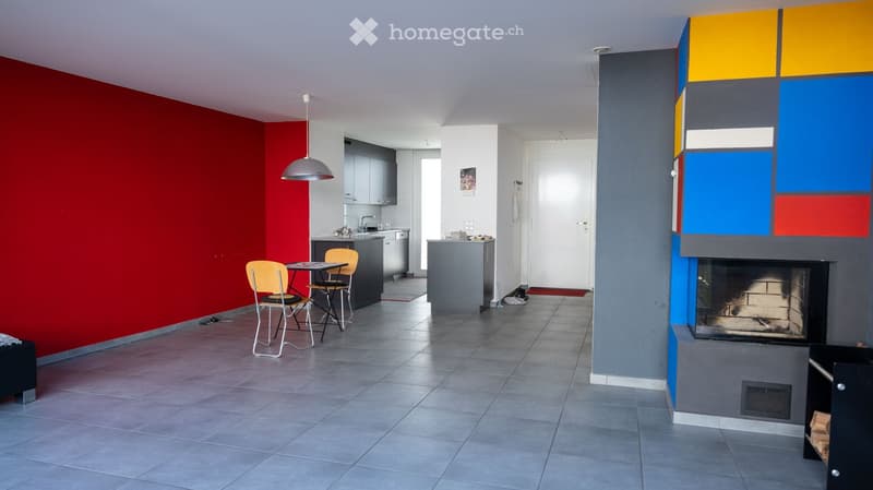 modern interior, red wall, gray floor, dining table, chairs, fireplace, kitchen area, gray cabinets, white door