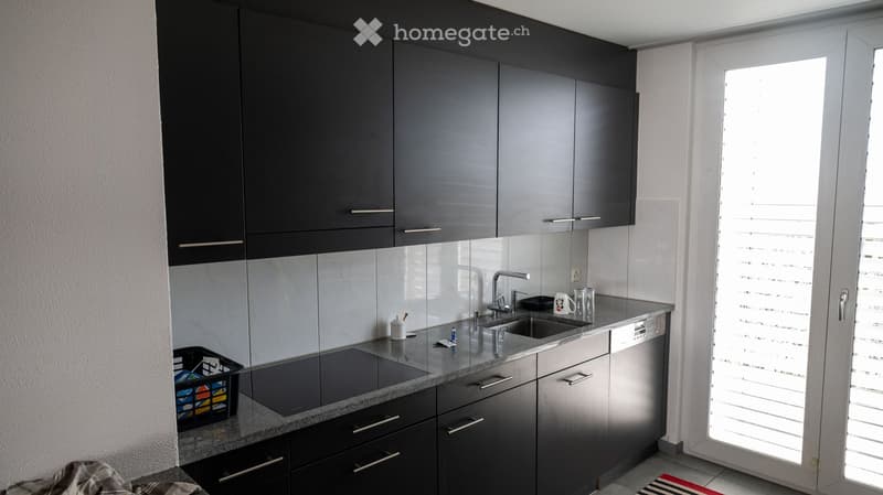 modern kitchen with black cabinets, granite countertop, induction stove, sink, dishwasher, faucet, white tiles