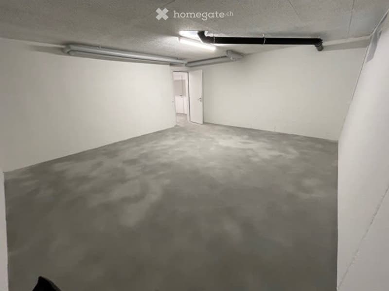 Empty room with white walls, gray floor, and a door.