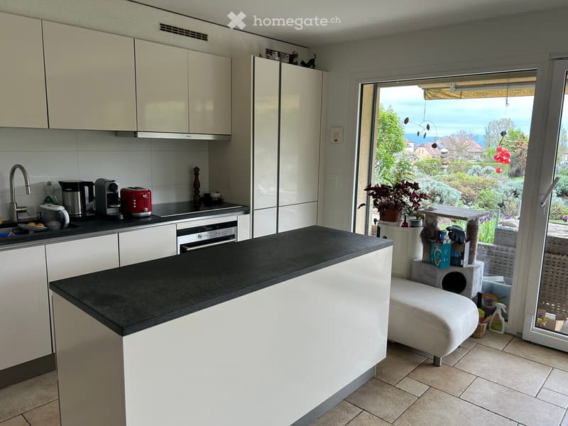 modern kitchen with white cabinets, black countertop, large sliding glass door, view of garden