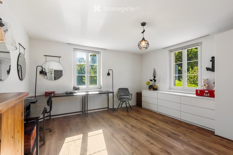 modern room with wooden floor, white walls, large windows, desk, chair, lamps, mirrors, storage drawers, decorative items