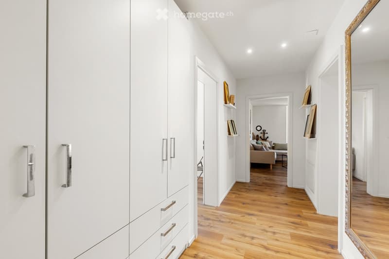 white walls, wooden floor, large white wardrobe, mirror, hallway
