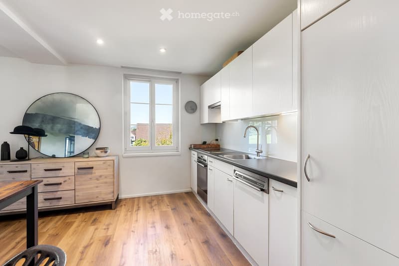 modern kitchen with white cabinets, wooden floor, round mirror, sink with faucet, dishwasher, window