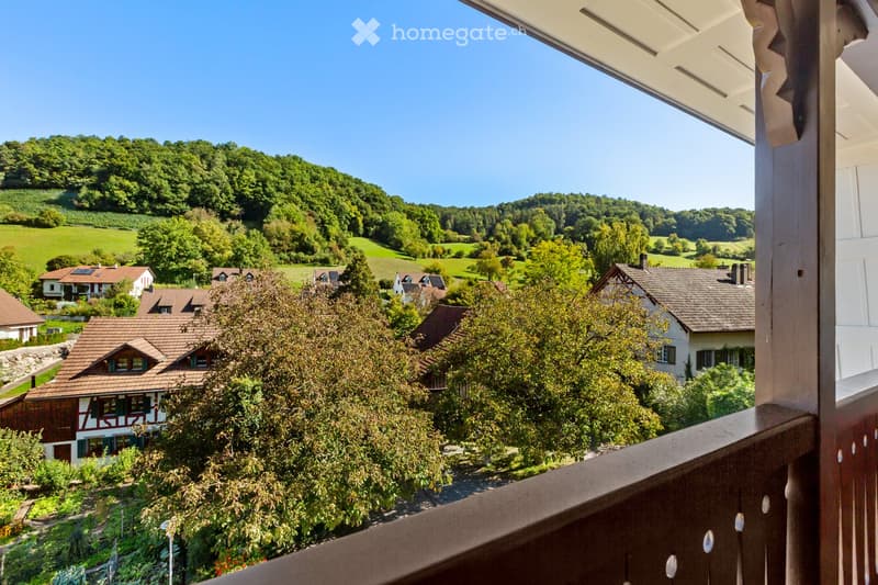 balcony with wooden railing, view of houses and hills