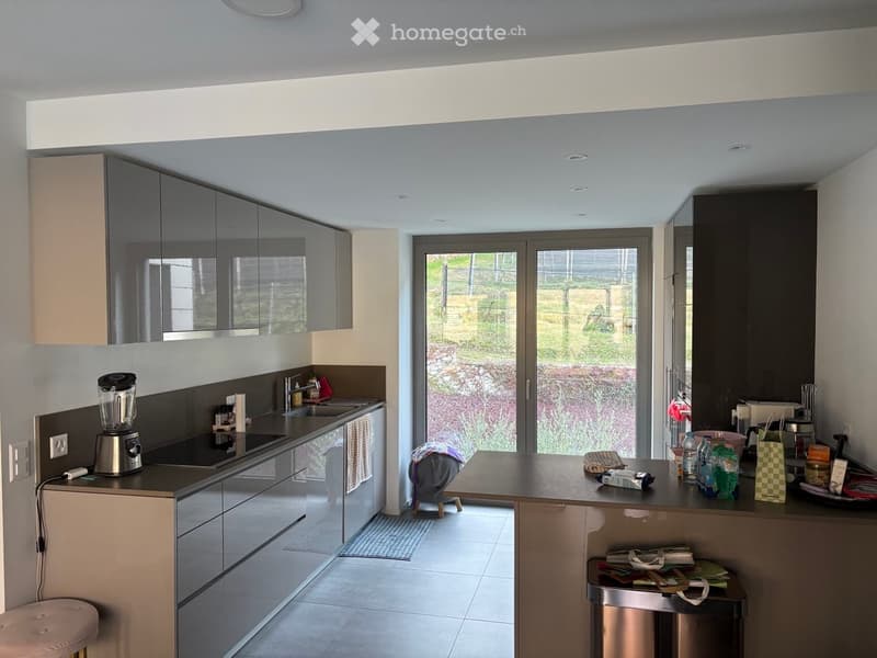 modern kitchen with large windows, stainless steel appliances, tiled floor, cabinets, countertop, sink, faucet, blender, trash can, stool
