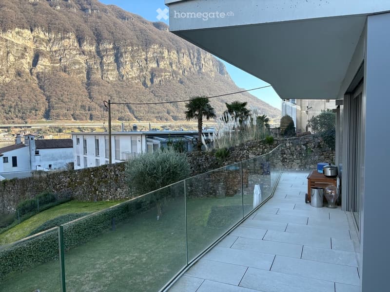 Balcony with glass railing, tiled floor, mountain view, small table with items
