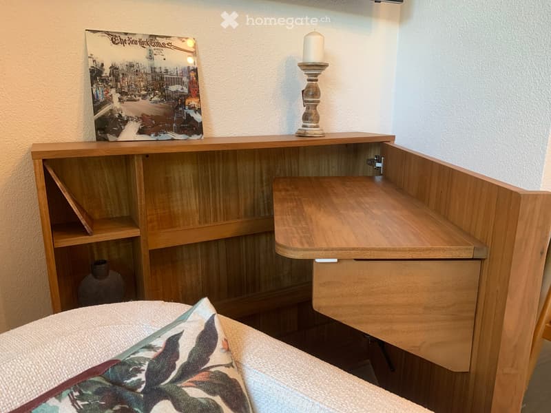 Corner desk with shelves, candle, picture, vase, bed with pillow