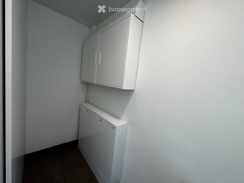 Empty room with white built-in cabinets and a dark tiled floor.