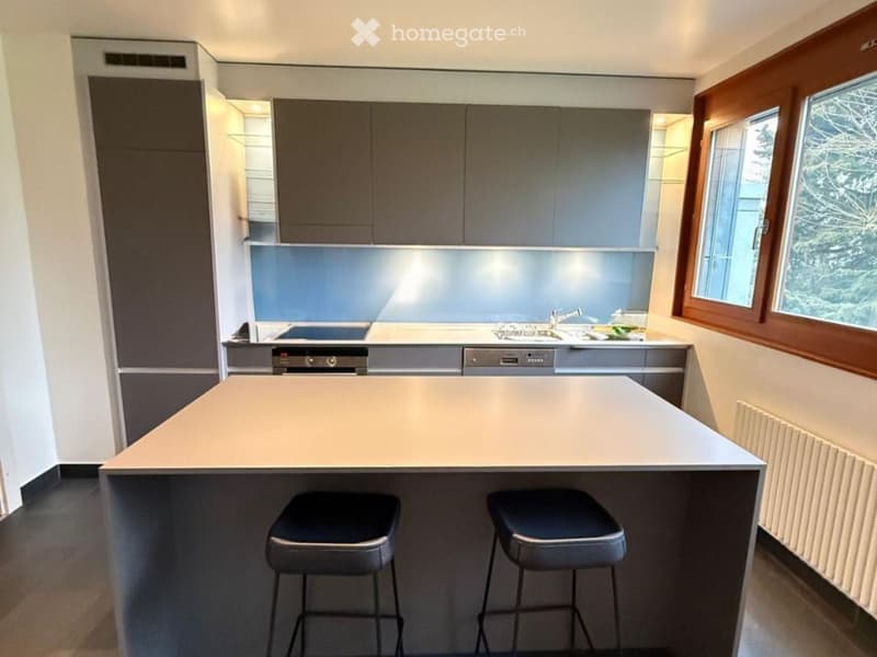 modern kitchen with island, gray cabinets, white countertops, two stools, dishwasher, large windows