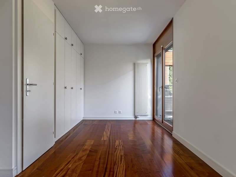 Empty room with wooden floor, white walls, white doors, sliding glass door, white radiator, power outlets