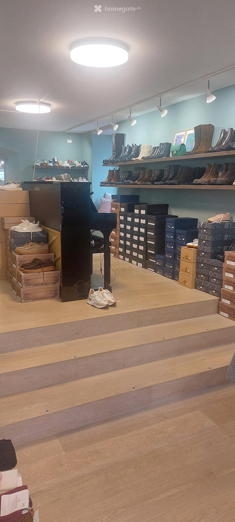 wooden floor, shelves with shoes, piano, boxes, lights on the ceiling