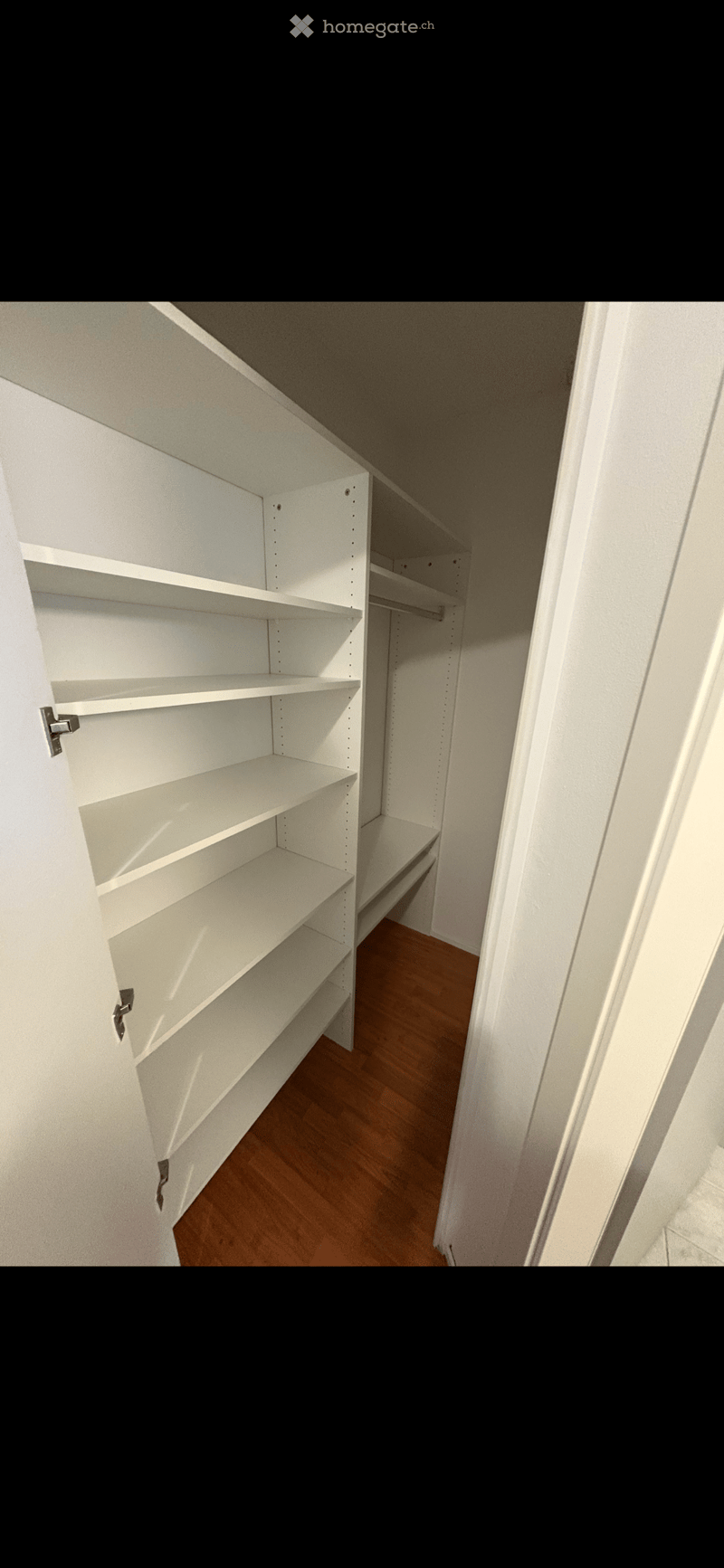 empty walk-in closet with white shelves and wooden floor
