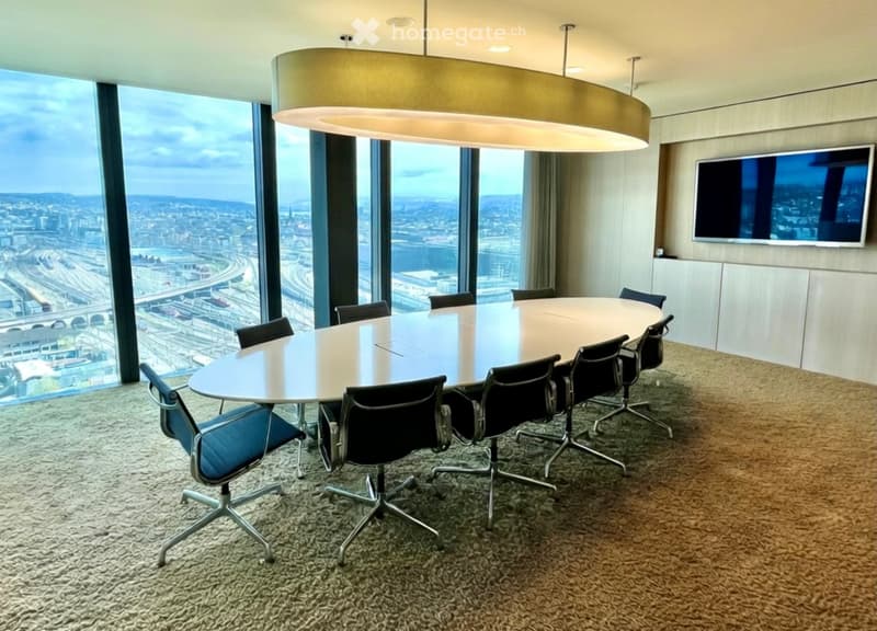 large oval table, black swivel chairs, large windows, city view, flat screen TV, large ceiling light
